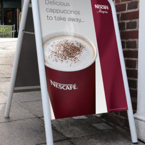 A photo of a Standard A-Board outside a shop with Nescafe artwork