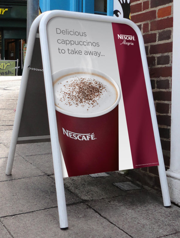 A photo of a Standard A-Board outside a shop with Nescafe artwork