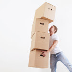 A photo of man trying to carry lots of boxes