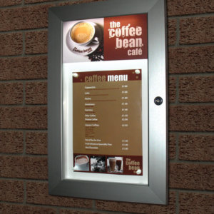 An illuminated menu display case mounted on a wall with display menu in place