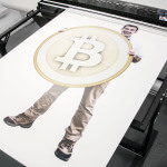 A photo of Glenn Wrigley being printed holding a giant Bitcoin